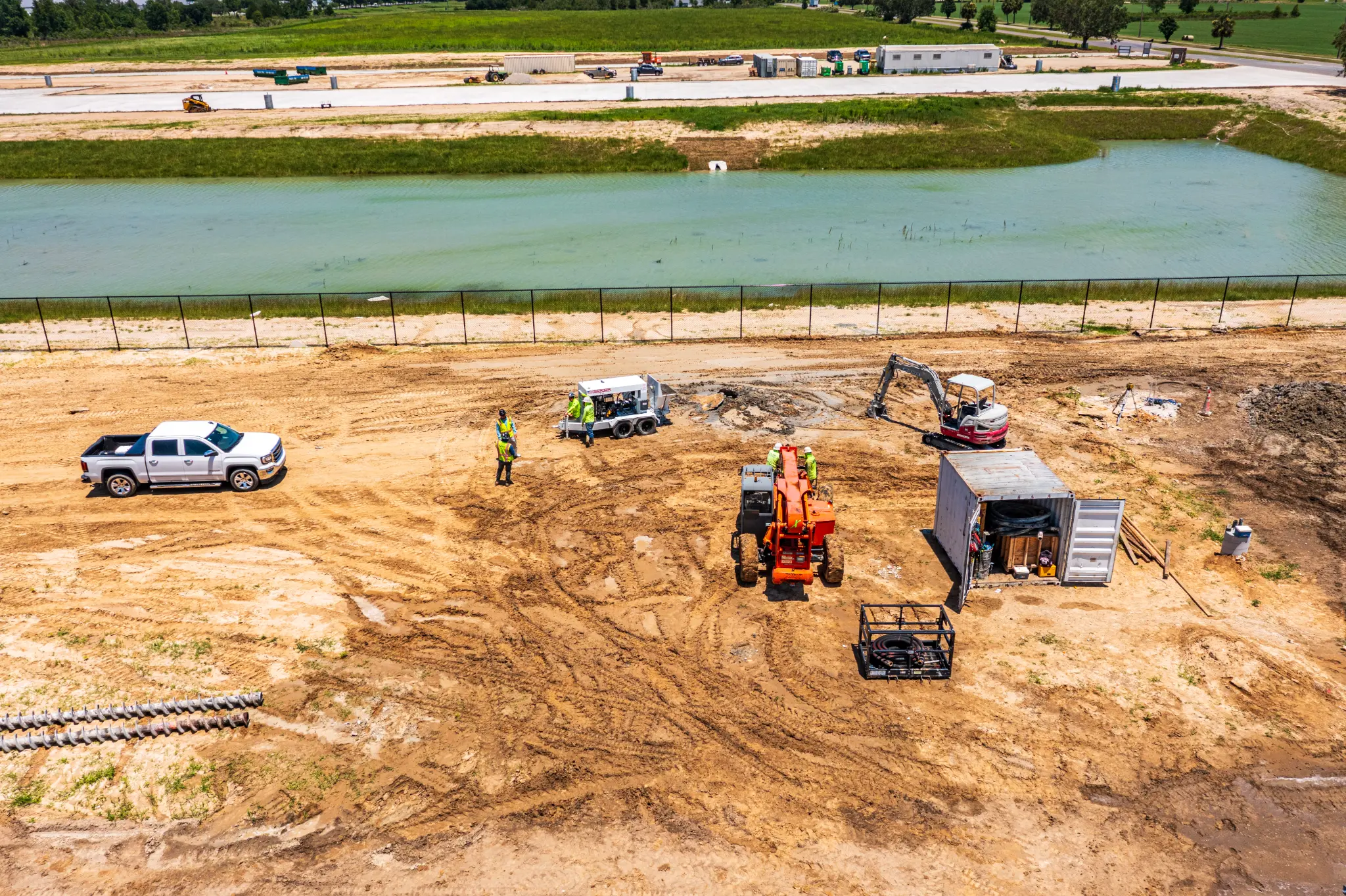 Aerial view of a JCB telehandler and crew working active sitework beside the retention pond at Ben E. Keith Foods, Alachua FL — Visit 66