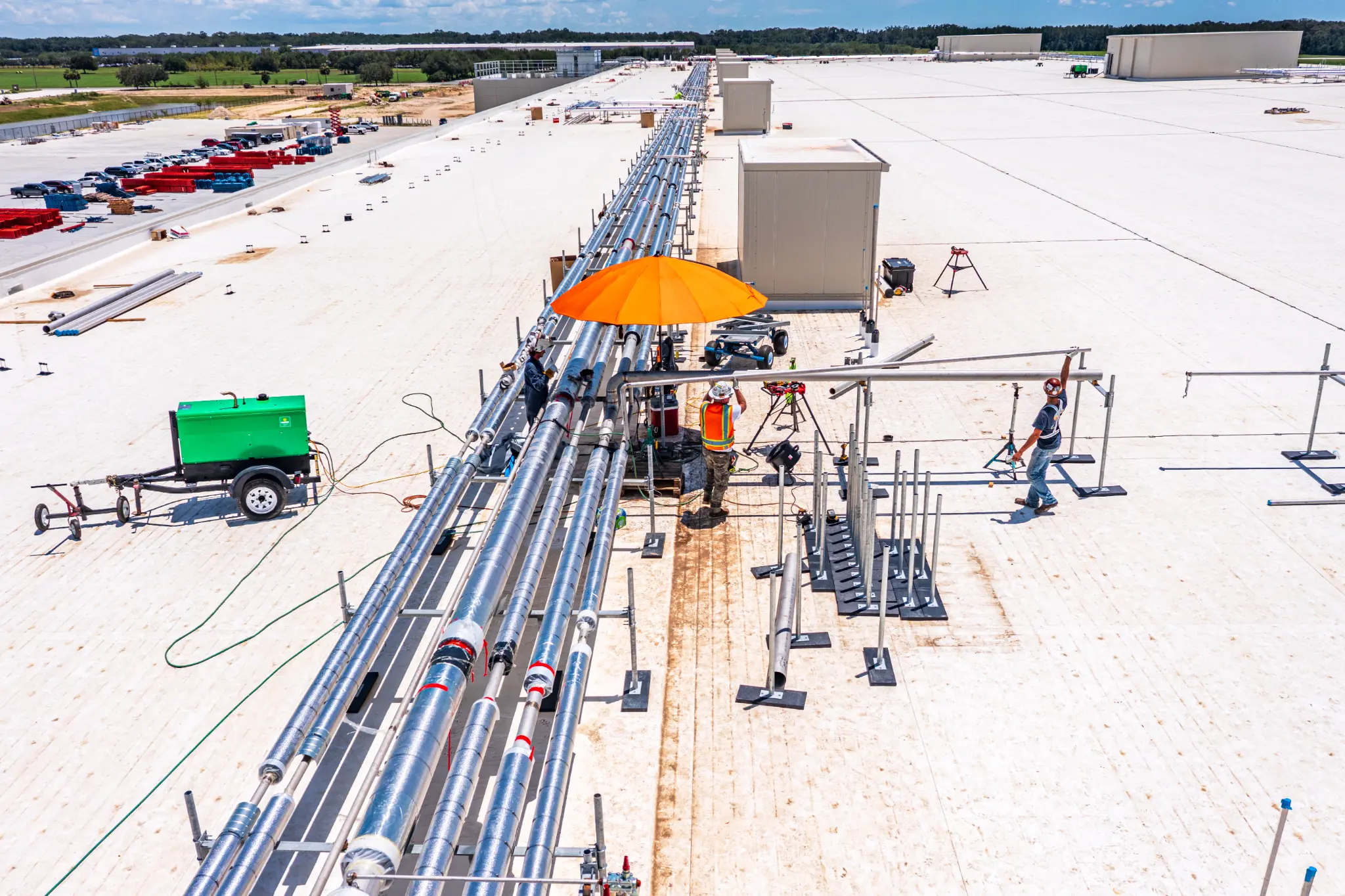 Workers installing rooftop HVAC ductwork on a large warehouse under construction in Alachua County, FL