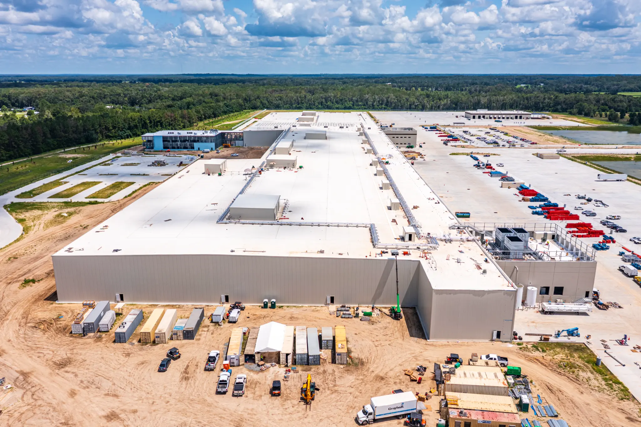 Wide aerial view of the Ben E. Keith Foods 707,000 sq ft distribution center under construction in Alachua, FL — roof complete, parking field and stormwater pond in progress