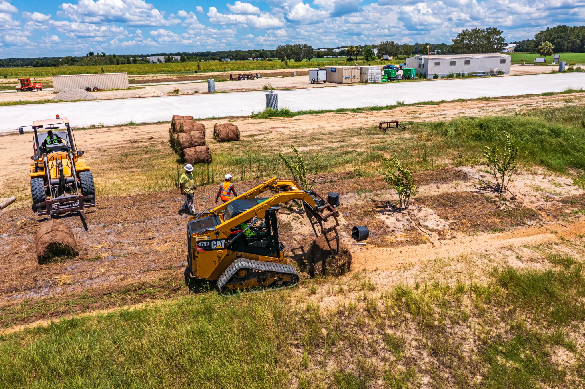 CAT skid steer and crew installing sod and landscaping at a commercial construction site in Gainesville, FL