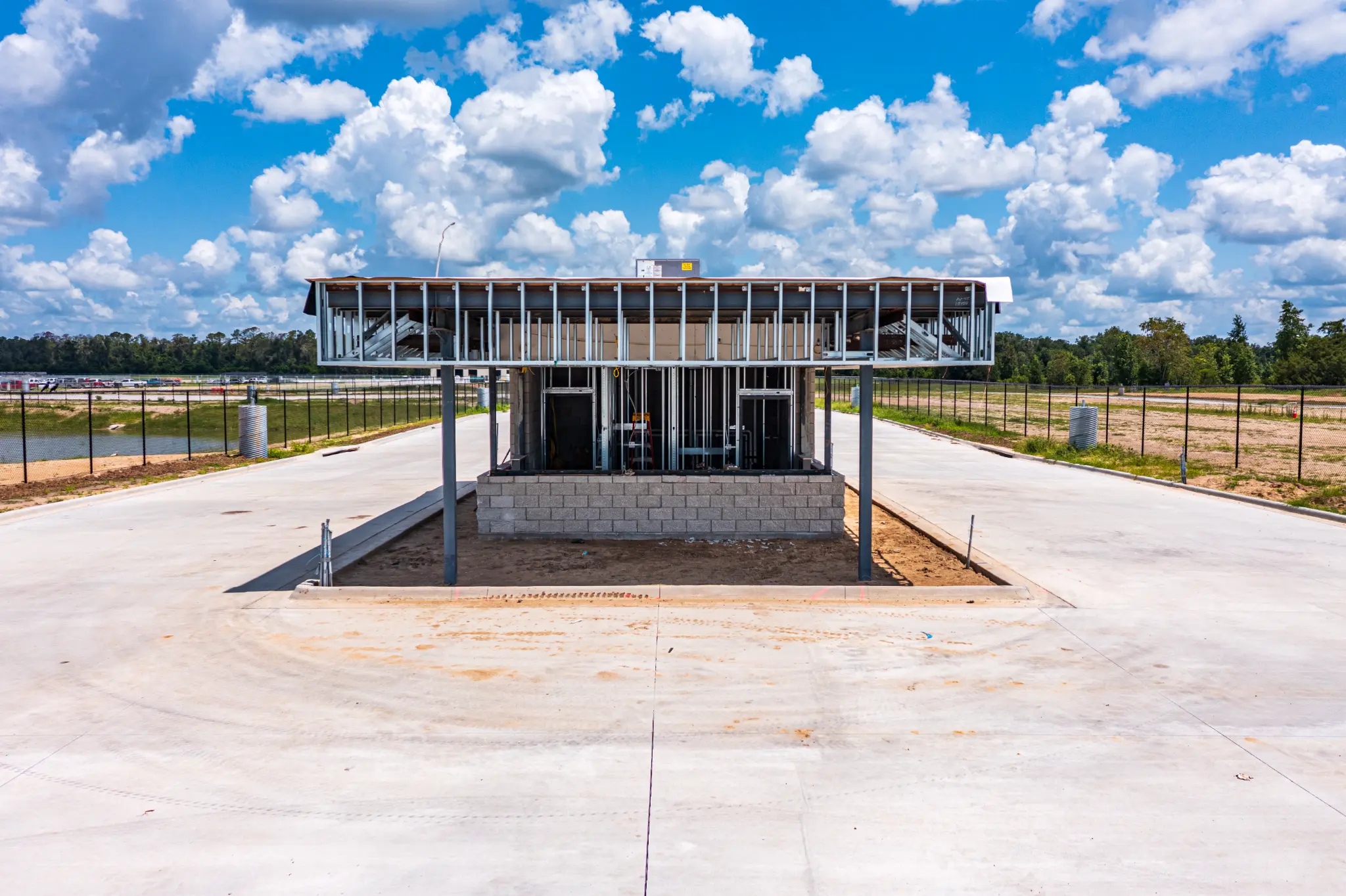 Steel-framed guardhouse canopy structure with CMU base and open concrete apron at the Ben E. Keith Foods campus entrance, Alachua FL — Visit 67