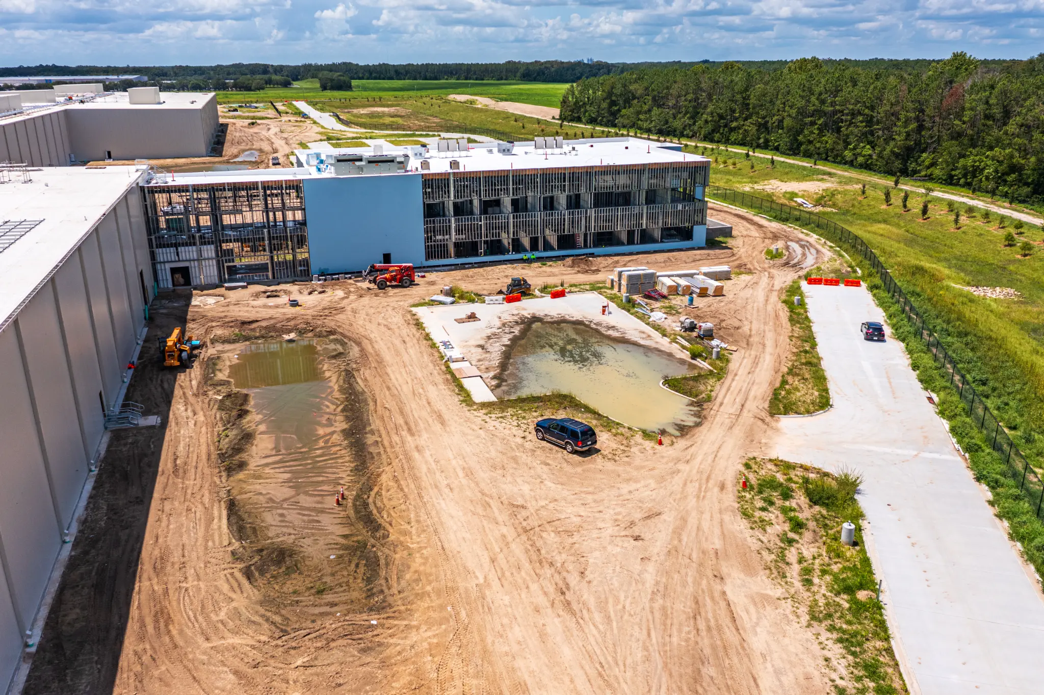 Aerial view of the multi-story office building under construction beside active sitework and stormwater ponds at Ben E. Keith Foods, Alachua FL — Visit 67